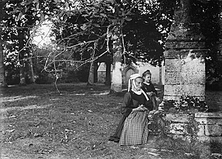 Femme et fillette priant devant le calvaire de la chapelle Saint Georges.