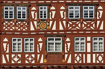 Detalhe da fachada da Palm’sche Haus na praça do mercado em Mosbach, distrito de Neckar-Odenwald, no norte de Baden-Württemberg, Alemanha. É a maior e mais magnífica casa em enxaimel da cidade. Segundo uma inscrição do edifício, a casa foi construída em 1610 pelo mestre construtor Abraham Lenger para o oficial de justiça Johann Schradmüller. O edifício recebeu a designação de Palm'sches Haus de um proprietário posterior, o comerciante Anton Palm, cujo nome está estampado na janela saliente de um dos cantos da construção. A casa provavelmente nunca foi rebocada devido ao seu enxaimel variado e extremamente decorativo, sendo amplamente remodelada em 1981/1982. (definição 6 054 × 4 000)