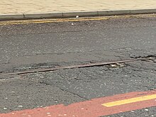 A pothole reveals old tram tracks under Lever Street, Manchester Pothole tram track, Manchester.jpg