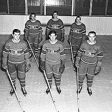 Černobílá fotografie šesti celovečerních hráčů Montrealu Canadiens.  Hráči jsou na ledě rozděleni do dvou řad a jsou připraveni hrát lední hokej