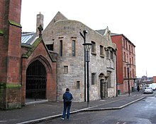To the south of the halls a tenement stands at the junction to Maryhill Road Ruchill Church Hall1.jpg