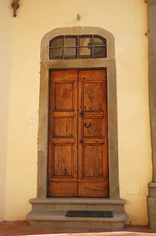 Foto a colori di una porta di legno abbastanza semplice in un muro bianco.