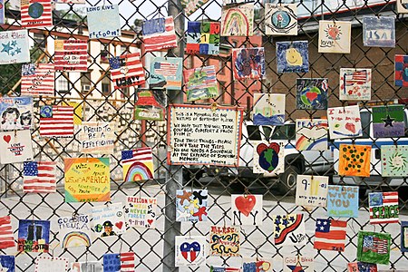 A small monument to the victims of the September 11th attacks on the fence of a car lot on Greenwich and Seventh Avenues in New York City.