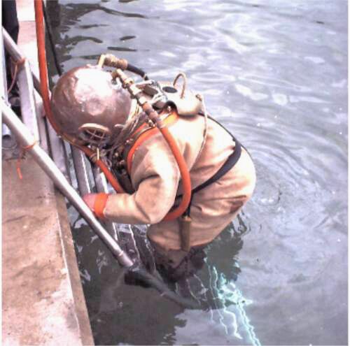 Diver in standard diving dress entering the water at Stoney Cove, England