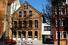 Kleinbürgerliches Wohnhaus in gelblichem Backstein An der Strangriede 13 aus dem 19. Jahrhundert mit Durchgang vom Edwin-Oppler-Weg zum Spielplatz an der Haltenhoffstraße