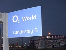 Sign for the boat landing at East-Side-Park, with the Berlin Wall and O2 World in the background Anlegestelle O2 World.jpg