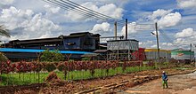 Worker walking near the boundary of an oil mill in Malaysia. Palm oil production is important part of economies in many parts of rural Malaysia, but is also a source of environmental conflict Balung Tawau Sabah Apas-Balung-Mill-02.jpg