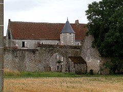 Generelt billede af en bygning med et rundt tårn, der stikker ud fra en omgivende mur, der er gennemboret af en porte-cochère.