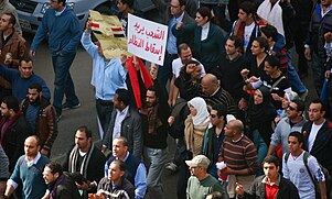 Protesters on the Day of Rage, January 28, 2011. The sign reads "lsh`b yryd sqT lnZm" which translates to "the people want the fall of the regime". Crowd of protesters in Cairo during the 2011 Egyptian Revolution (5).jpg