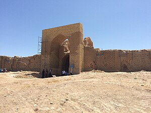 Main gate of the 11th-century Dayahatyn caravansaray in Lebap velayat, Turkmenistan. The gate is made of adobe bricks and sits in a dry, sandy area.