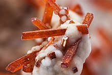 Dundasite is the snow like mineral encasing crocoite Dundasite and Crocoite.jpg