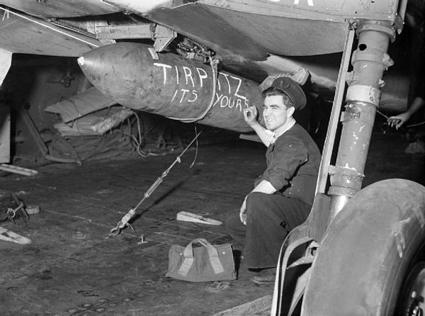 A Fleet Air Arm crewman chalks a message on the 1,600-pound bomb carried by a Fairey Barracuda of HMS Furious