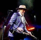 A man in a purple suit and a hat playing the dobro.