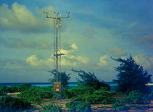 Una estación meteorológica en una isla azotada por el viento, con algunos pequeños arbustos y árboles.