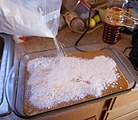 A prepared cake mix is spread on top of canned pumpkin pie filling in a rectangular baking dish.