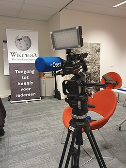 Op de foto is een camera te zien van RTV Oost en een banner van wikipedia