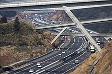 画像左 : 静岡県富士市内。往復6車線を前提に着工され、その後2003年の第1回国幹会議の決定で暫定4車線で整備するように計画変更した経緯から6車線分の幅がありながら4車線に縮小された[24]。 画像右 : 御殿場JCTに近接する今里トンネル。左右のトンネルの離隔はわずか4 - 6 m。土被りも少なく、地質も富士山噴火により流れ出た自立性の悪い自破砕溶岩層を含み、地盤改良なしでは掘削不可能であった[202]。こうした悪条件下で片側2車線断面を3車線断面に拡幅することは困難であるため、当初から完成断面で掘削された[203]。