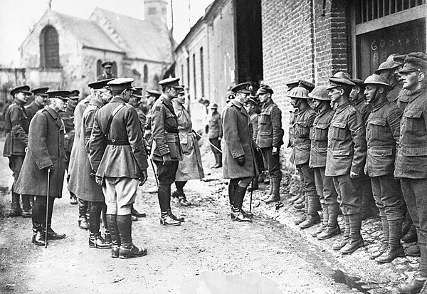 King George V, escorted by Lieutenant Colonel Reginald B. Rickman and Captain W. Foster MC, talking to Private Denny and the remainder of the 7th (Rob