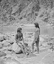 Black and white view of two men on the rocky bank of a river