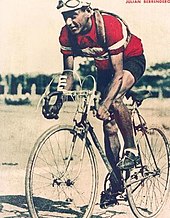 Photographie d'un cycliste sur son vélo, portant un maillot rouge.