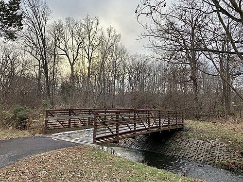 A bridge over a running river in winter, with some snow on the ground