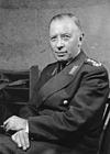 A black-and-white photograph of a smiling man sitting down in civilian clothing.