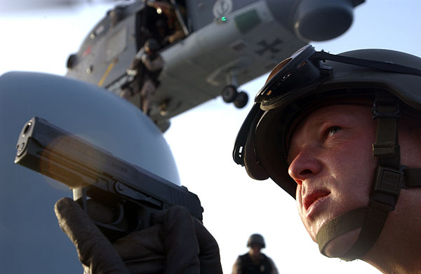 A German Navy boarding team member assigned to the frigate Augsburg (F213) provides security with a P8 pistol for the remainder of his team as they bo