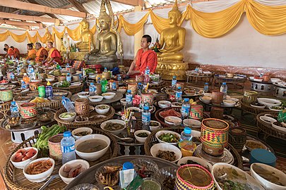 Divers plateaux avec des bols de nourriture et des kratips décorés, cuisinés pour les bonzes du temple de Don Det lors d'une cérémonie. Ces préparations sont cuisinées chez eux par les voisins, puis apportées sur place pour y être consommées. Janvier 2021