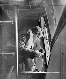 An aircrew sergeant of No. 209 Squadron RAF about to launch a carrier pigeon from the side hatch of a Saro Lerwick flying boat Royal Air Force Coastal Command, 1939-1945. CH2359.jpg