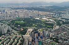 Der rechteckig geschnittene Olympic Park Seoul liegt inmitten dichter urbaner Bebauung. Die westliche Hälfte ist als Landschaftspark gestaltet, die Sportstätten konzentrieren sich in der östlichen Hälfte. Daran anschließend erkennt man die Hochhäuser im fächerförmig angelegten olympischen Dorf.