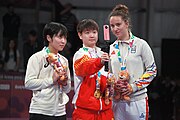 Deutsch: Tischtennis bei den Olympischen Jugend-Sommerspielen 2018: Tag 4, 10. Oktober 2018, Mädchen-Einzel, Siegerehrung - Gold: Yingsha Sun (CHN), Silber: Miu Hirano (JPN), Bronze:Andreea Dragoman (ROU)); Medaillen überreicht durch IOC-Mitglied Ching-kuo Wu (TPE), Maskottchen überreicht durch ITTF-Vize-Präsident Masahiro Maehara (JPN) English: Fencing at the 2018 Summer Youth Olympics at 10 October 2018 – Girls' single medail ceremony – Gold: Yingsha Sun (CHN), Silber: Miu Hirano (JPN), Bronze:Andreea Dragoman (ROU)); Medal presenter: IOC member Ching-kuo Wu (TPE), Mascot presenter: Vice-President Executive of the ITTF Masahiro Maehara (JPN)