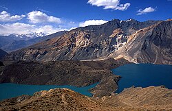 Vue en 1995 du barrage Usoi (au centre) et de l'éboulement l'ayant causé (au fond, de couleur claire) retenant le lac Sarez (sur la droite) et le lac Shadau (sur la gauche) ; l'écoulement du lac Sarez se fait en arrière plan vers l'ouest et non vers le lac Shadau.