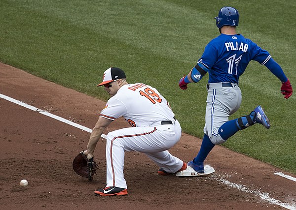 Kevin Pillar of the Toronto Blue Jays reaches first base safely as Chris Davis of the Baltimore Orioles attempts to scoop a bouncing ball thrown by on