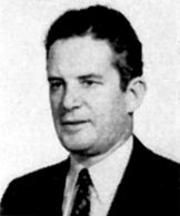 Grainy older portrait of a man wearing a suit and a tie. He is facing left, and has brown curly hair.