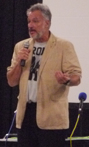 John de Lancie, wearing a "Brony" shirt, addresses the attendees of the 2012 Summer BronyCon