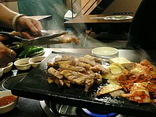 Cooked samgyeopsal being cut with scissors