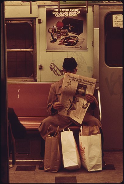 File:LEXINGTON AVENUE LINES SUBWAY PASSENGER PASSES THE TIME BY READING A NEWSPAPER. GRAFFITI DEFACES THE WALL BEHIND HIS... - NARA - 556659.jpg