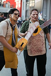 Photo de deux hommes habillés en bouchers et munis d'une tronçonneuses dans la rue en plein jour.