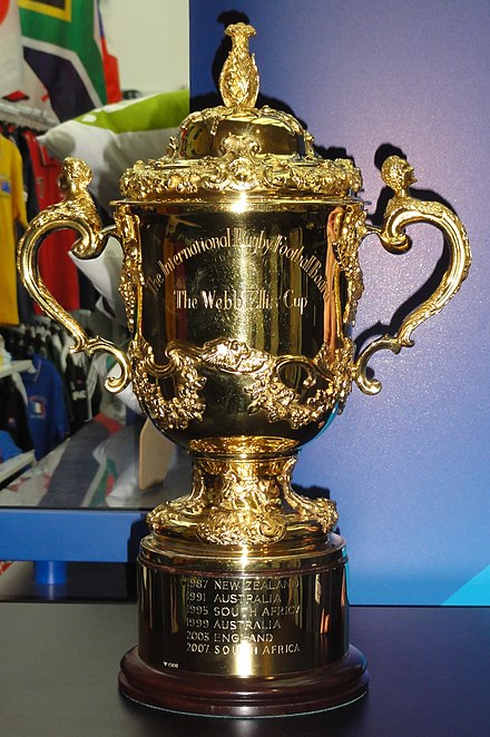 A gold cup with two handles inscribed with "The International Rugby Football Board" and "The Web Ellis Cup"