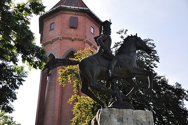 Jan Henryk Dąbrowski monument with a historic water tower in the background