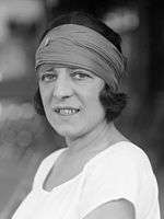 A woman looking at the camera with a colored bandanna on and a white shirt, which this picture is black and white