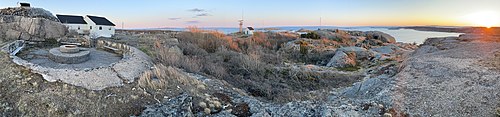 Utsikt fra Tjønneberget sørover på turområdet mot Oslofjorden, med sola som går ned over naboøya Tjøme i vest. Bildet viser også ruiner etter tyskernes lyskasterstasjon, DNTs overnattingshytte i huset etter Forsvaret og Kystverkets radarantenne. Forvrengt panorama: April 2021