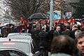 Čeština: Protestní událost "Přivítání Miloše Zemana červenými kartami" během třídenní návštěvy prezidenta Miloše Zemana v městech jižní Moravy, uspořádaná v pondělí 1. prosince 2014 od 11:30 před budovou Univerzity obrany na Kounicově 44. Prezident vystupuje ze svého vozu a příslušník ochranky mu nabízí deštník, aby ho chránil před mrznoucím deštěm.