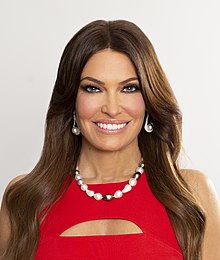 Guilfoyle posing and smiling in a red dress