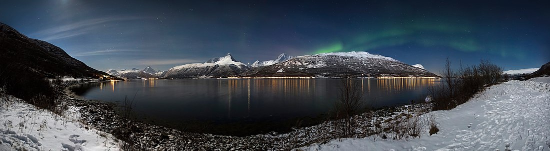 A wide view over Storfjorden (a part of Lyngen fjord) in a winter night in 2012 March. Aurora borealis (known as the northern lights) are running across the sky.
