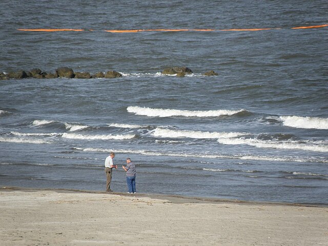 Two men collecting oil samples from the Deepwater Horizon oil spill at a beach in Grand Isle in May 2010