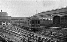 A Mersey Railway electric multiple unit (EMU) having just departed from Birkenhead Park for Liverpool. Mersey Railway (All About Railways, Hartnell).jpg