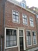 Huis met gepleisterde langsgevel, gootlijst op klossen