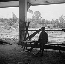 A Dutch soldier sitting at the Klender Station as Staatsspoorwegen's legacy (1946) Militair op wacht bij het station van Klender, Bestanddeelnr 255-6842.jpg