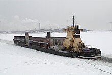 Pusher Rautaruukki with the barge Botnia outside Raahe, Finland, with the Raahe Steel Works in the background. Rautaruukki-botnia 20110207.jpg